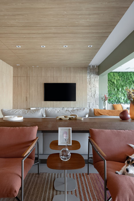 sala com poltronas, objetos em tons de rosa e verde e tv