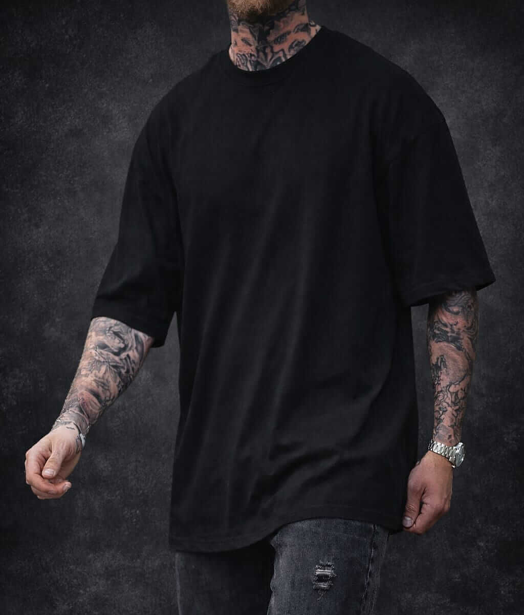 Man with tattoos wearing black oversized t-shirt