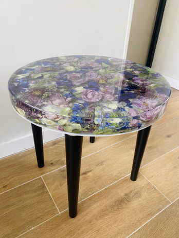 round table with preserved bridal bouquet flowers in purples and greens in epoxy resin with black table legs