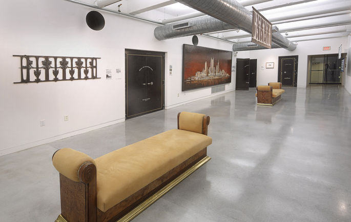 Wide installation view with Guimard’s balustrade, original vault doors, and hanging textiles.