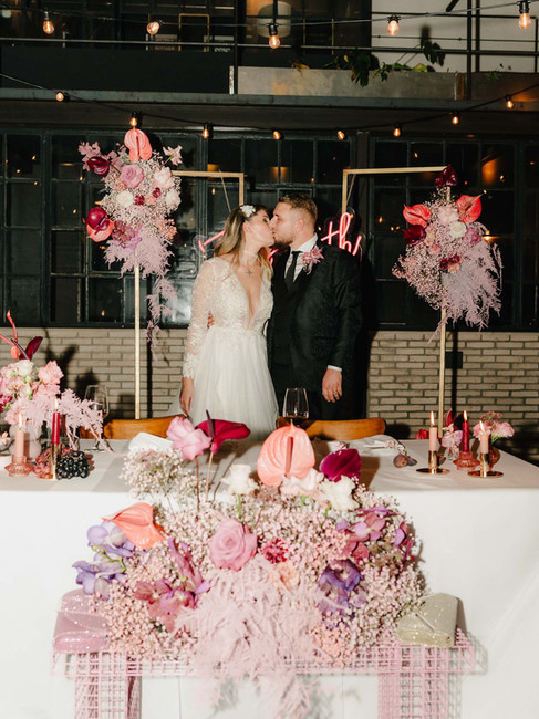 Liebevoll dekorierter Hochzeitstisch mit rosa Blumenarrangement und modernen Details