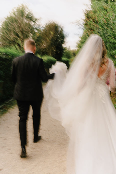 Brautpaar läuft Hand in Hand über einen Weg