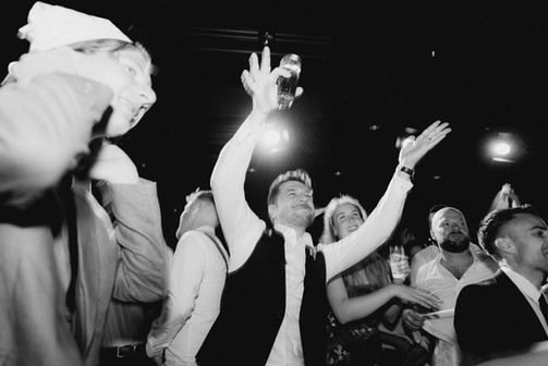 Gruppe von Gästen feiert mit erhobenen Händen und Drinks, ausgelassene Stimmung.