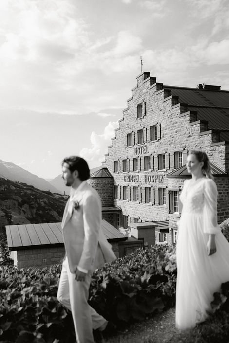 Brautpaar steht vor einem alpinen Berghotel.