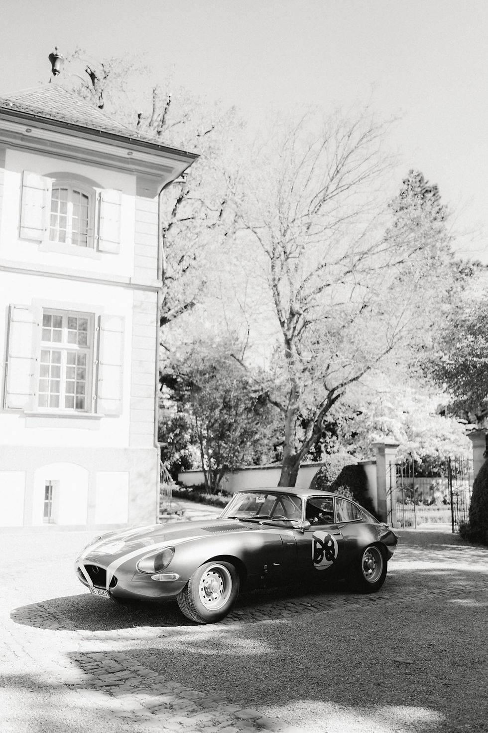 Ein Oldtimer steht vor dem Schloss Bümpliz, aufgenommen in schwarz und weiss.