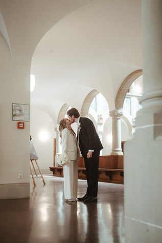 Braut und Bräutigam küssen sich im Foyer des Zürcher Stadthauses, umgeben von Bögen und Licht.