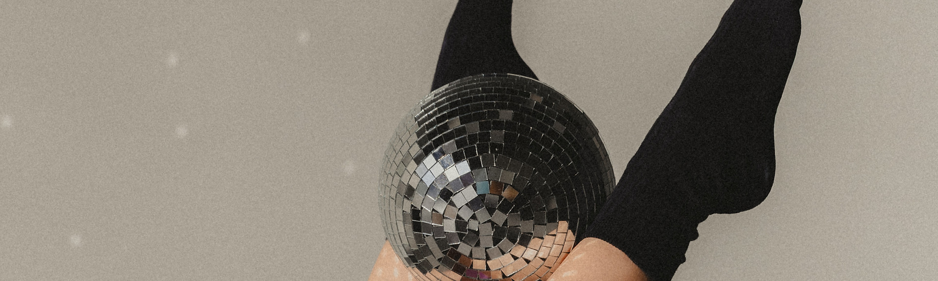 Lifestyle foto van benen gestrekt omhoog in pilates pose met discobal tussen de benen in zacht studiolicht.