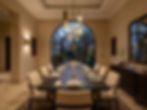 A luxury dining room in a Riyadh villa — a large natural stone table with generously upholstered chairs, a sculptural pendant over the centre of the table, and a lighting scheme that creates warmth and intimacy at eye level