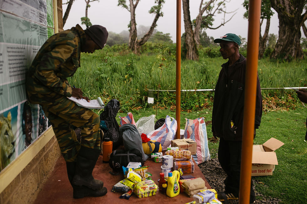A porter and Kenyan Wildlife Service agent checking inventory in preparation for a 4 -day Mount Kenya expedition.