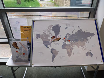 Indoor display of a world map poster and shoe cutout with Look how far we’ve come! and Park Ward Around the World Challenge.
