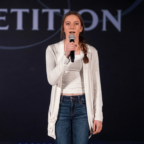 Female vocalist in white cardigan performing with microphone at Royal Dance Competition vocal competition