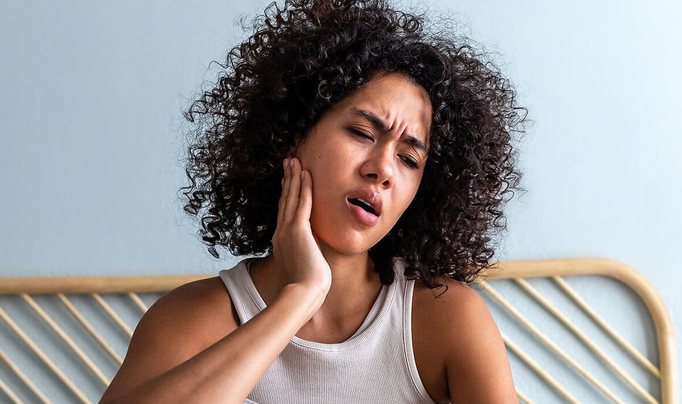 Woman holding one side of her jaw in pain while sitting at home, showing symptoms of sudden one-sided jaw pain that may require evaluation by a dentist wilmington nc.