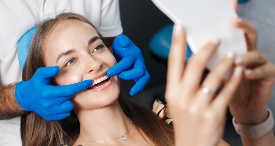 Patient checking her smile in a mirror during a cosmetic dental consultation with a dentist in Wilmington NC discussing smile improvement options.
