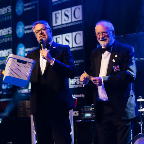 Live auction moment on stage at the Humber Rescue Gala Ball 2025 lifeboat charity event. Dave Roberts - Chairman and Blair Jacobs host announcing golden envelope winner
