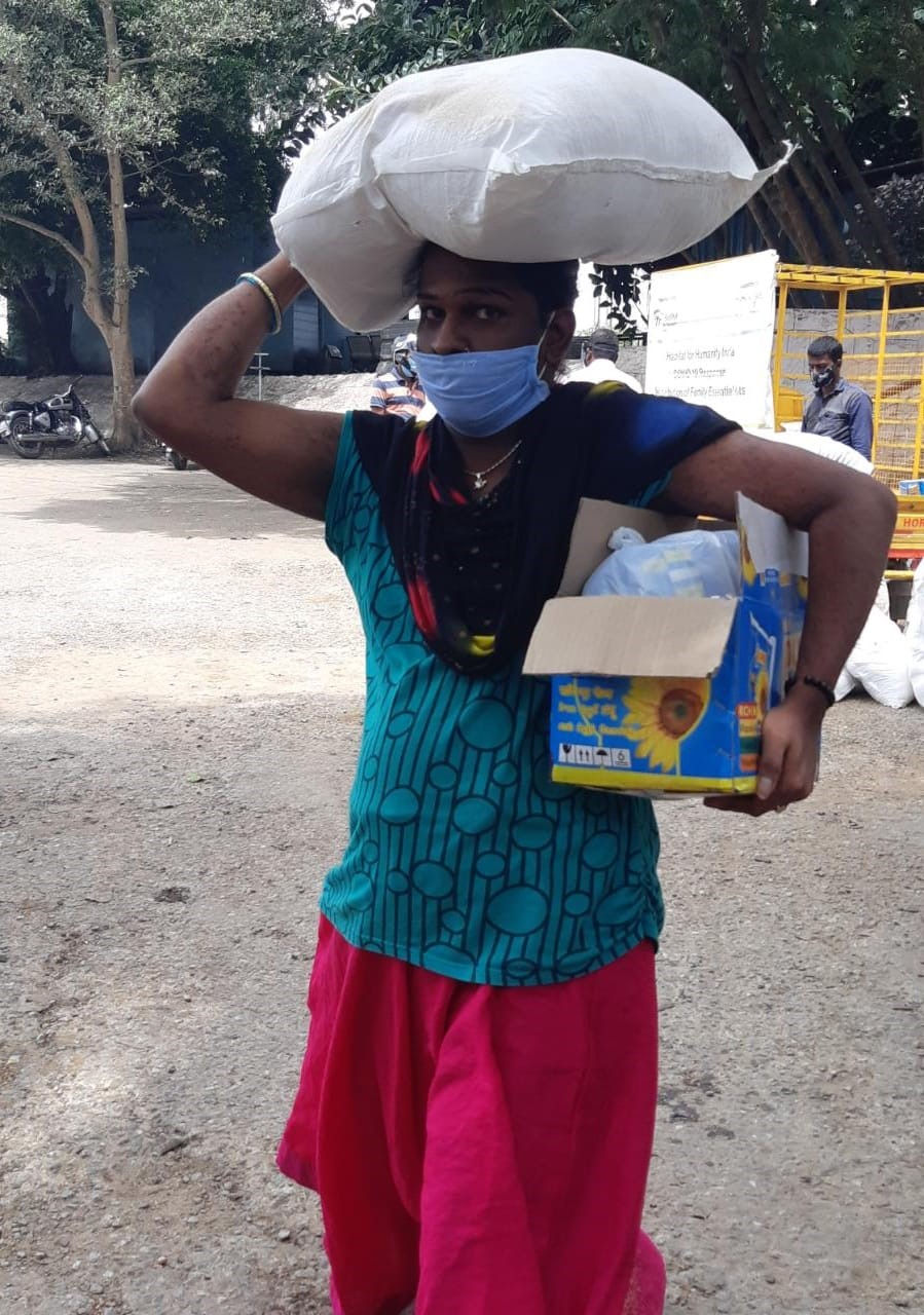 A transgender person carries a free monthly ration kit at a Reach Lives camp