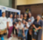 Group of smiling women posing in front of a Paytm booth. Some wear "REACH LIVES" shirts. Background features a patterned wall. Energetic mood.
