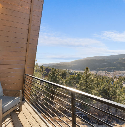 A-frame cabin balcony with a chair overlooking scenic Southern Utah desert landscape and surrounding natural views.