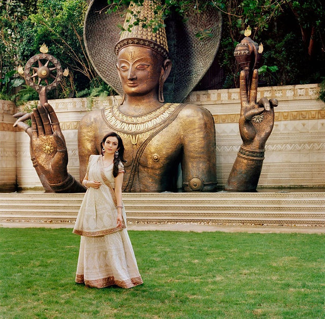 Nita Ambani poses in front of a large outdoor sculpture.