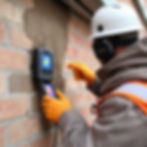 Eye-level view of a home inspector examining a basement wall for signs of moisture intrusion