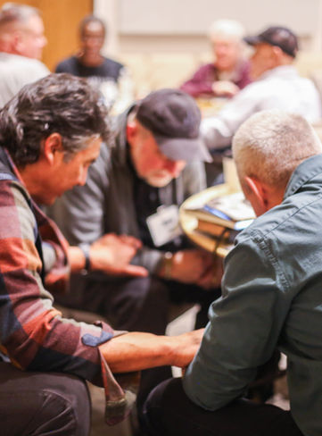 Men gathered in prayer at Breakfast & Livestream event.