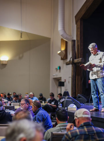Speaker reading from a bible at a breakfast livestream.