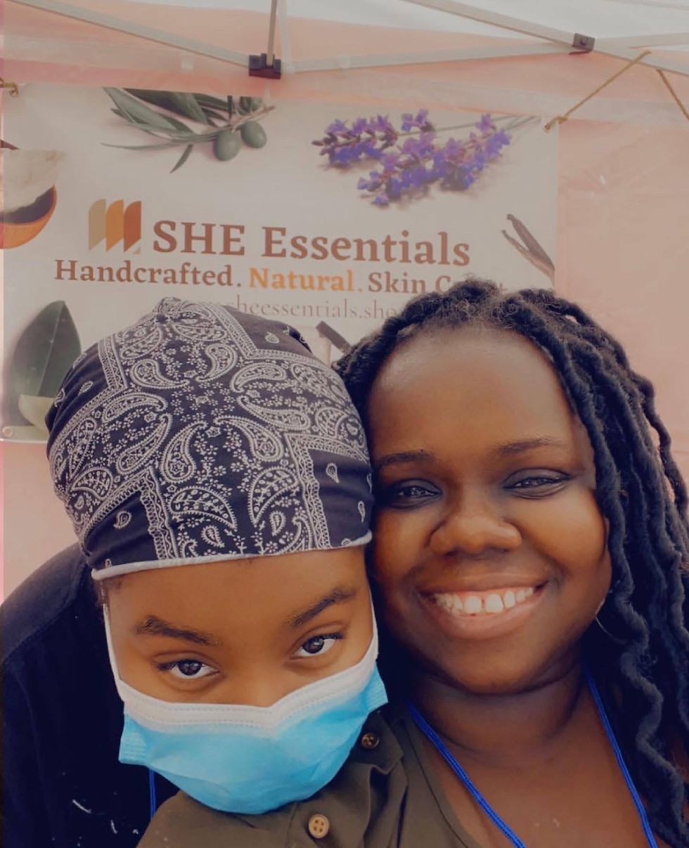 SHE Essentials founder and family promoting healthy nourishing skincare at outdoor market.