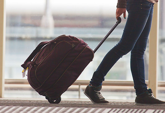 Person Rolling Suitcase in Airport