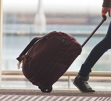 Person Rolling Suitcase in Airport