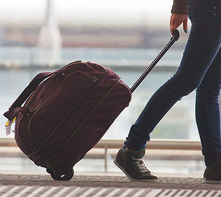 Person Rolling Suitcase in Airport