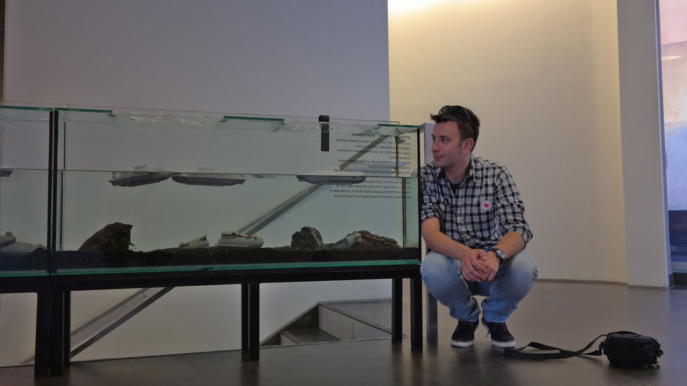 Man observing concrete submarine models floating in a tank.