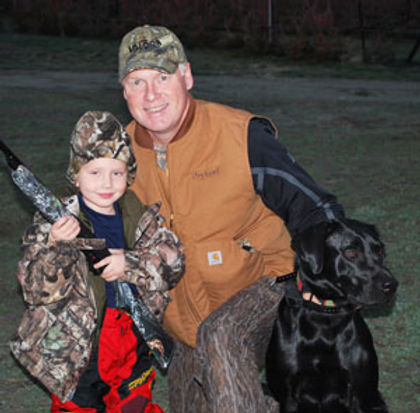 Black lab with owner and child out hunting