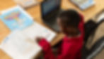 young boy at laptop reading workbook