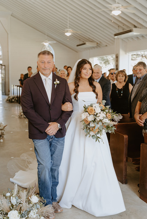 Bride walking down the aisle with her father during the wedding ceremony at The Chandelier of Gruene in Gruene, Texas.