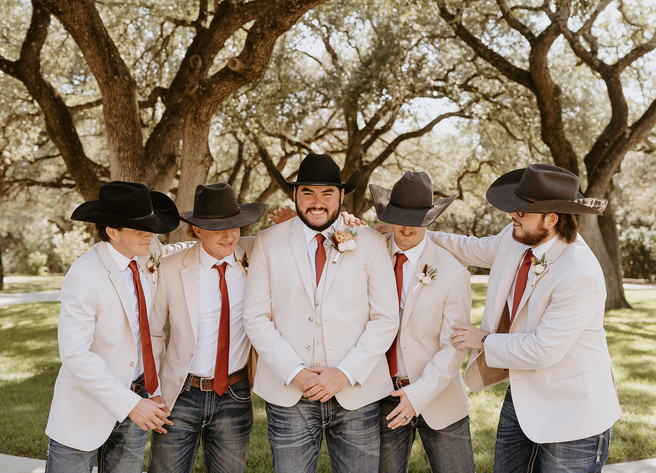 Groom and groomsmen laughing together while getting ready at The Chandelier of Gruene in Gruene, Texas.