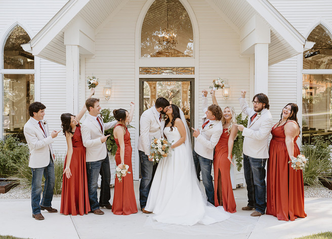Wedding party cheering as the bride and groom share a kiss at The Chandelier of Gruene in Gruene, Texas.