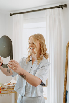 Bride looking at her reflection while having makeup applied before her Wimberley wedding at The Waters Point in the Texas Hill Country