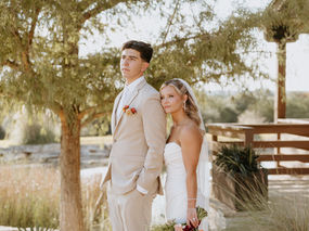 Ashton & Caleb embracing in front of Hidden River Ranch venue, warm Central Texas wedding photographer capturing golden hour portraits