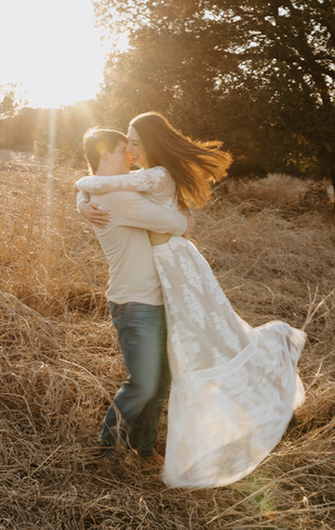Groom to be spinning her around during their engagement session in a field at Dinosaur Valley State Park near Glen Rose, Texas