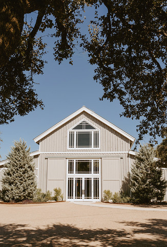 Wide view of the white barn at The Addison Grove wedding venue in Dripping Springs, Texas, photographed by Grace J Photo, a Texas Hill Country wedding photographer.