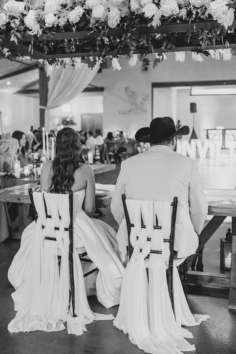 Moody portrait of the bride and groom seated together at their head table during the reception.