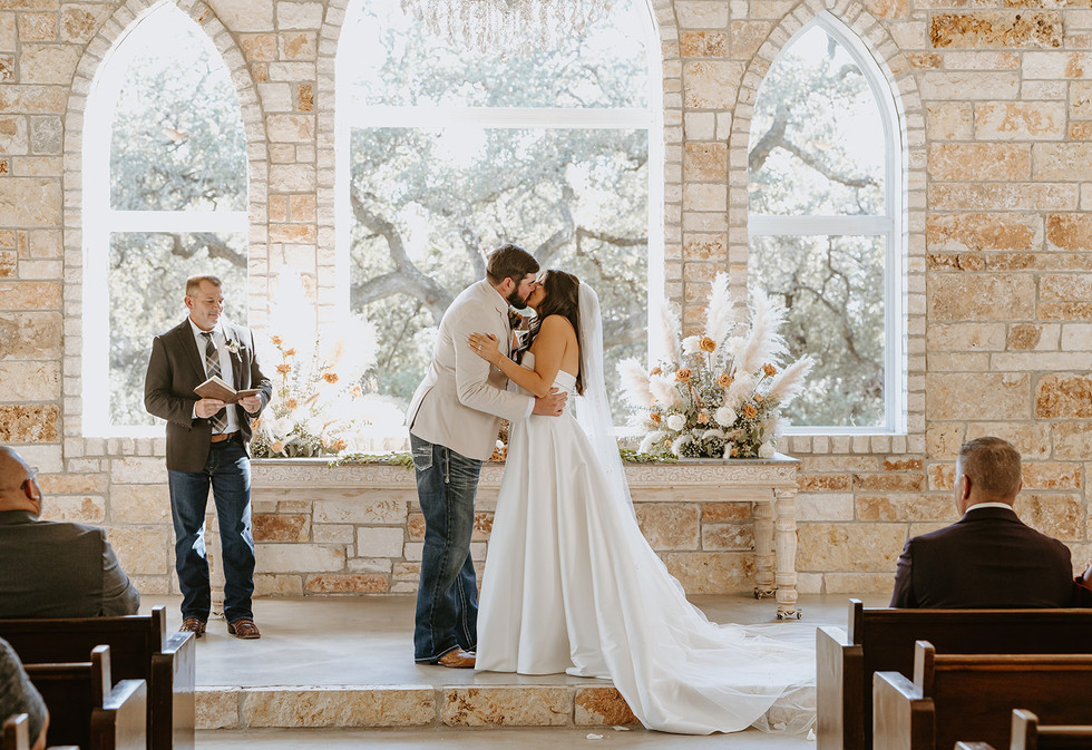 Bride and groom sharing their first kiss as newlyweds at The Chandelier of Gruene in Gruene, Texas.