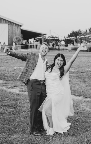 Bride and groom cheering at the camera in front of reception at Camp Hideaway in Fredericksburg, Texas