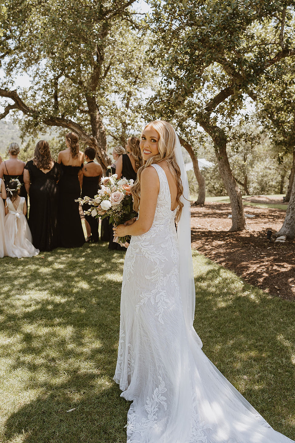 Bride peeking back before first look at Canyonwood Ridge in Dripping Springs wedding