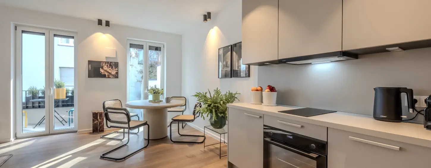 Offene Küche mit Blick auf Essbereich und Balkon in einem vollständig möblierten Apartment XL