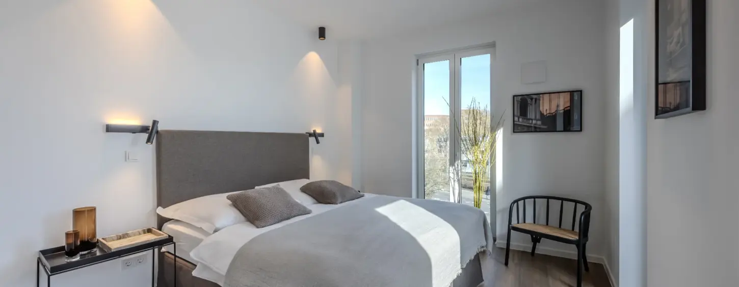 Schlafzimmer mit Leseleuchten und Balkonzugang in einem vollständig möblierten Apartment XL, Frankfurt