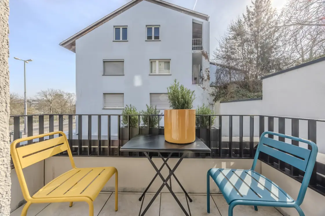 Balcony with colorful outdoor seating and city views in a fully furnished Apartment XL