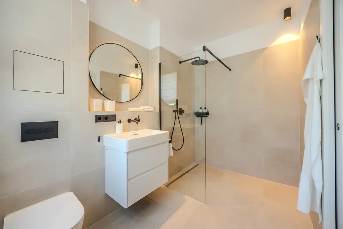 Bathroom with floating vanity, round mirror and framed art in a fully furnished apartment
