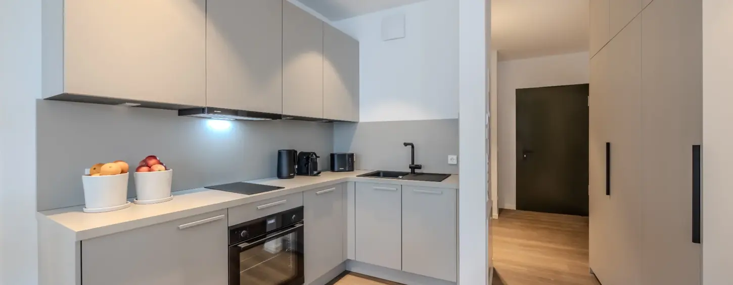 Einbauküche mit Blick zum Eingangsflur in einem vollständig möblierten Apartment XL