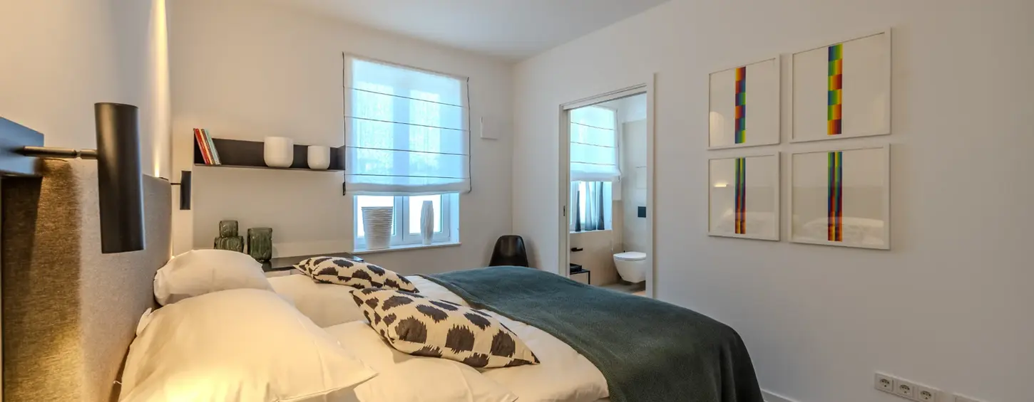 Schlafzimmer mit offenen Regalen und farbenfroher Wandkunst in einem vollständig möblierten Apartment L, Frankfurt