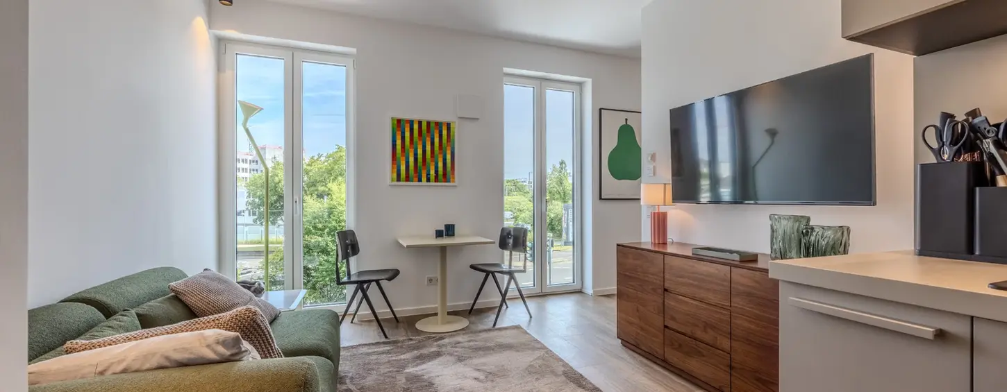 Wohnbereich mit Smart-TV und Esstisch in einem modernen, vollständig möblierten Apartment in Frankfurt